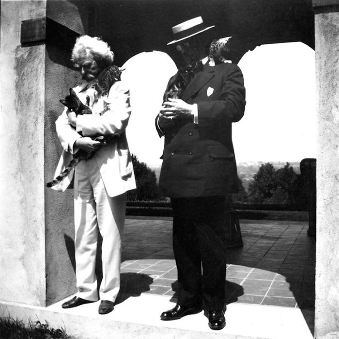Mark Twain holding cats next to a man